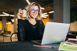 Blonde junge Frau am Laptop mit Kaffeebecher Blonde junge Frau am Laptop mit Kaffeebecher © designed by Freepik
